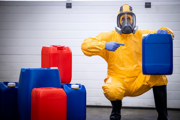 Photo ouvrier d'usine portant un masque à gaz pointant le doigt vers la cartouche en plastique contenant des produits chimiques