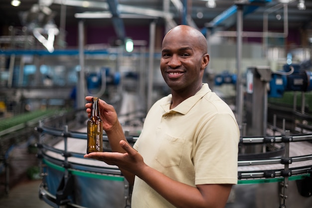 Ouvrier d'usine souriant tenant une bouteille vide