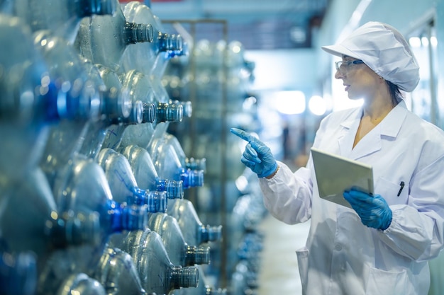 Un ouvrier d'usine vérifie les bouteilles d'eau dans l'entrepôt de l'usine industrielle