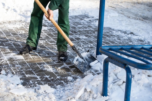 Un ouvrier utilise une pelle en métal pour briser des morceaux de glace gelés sur le trottoir