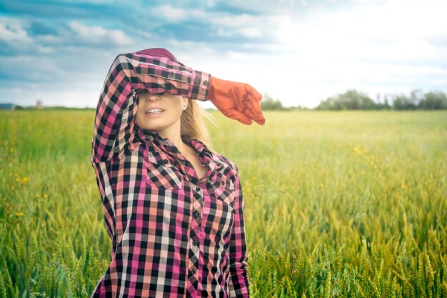 Ouvrière agricole fatiguée sur le fond d'un champ de blé