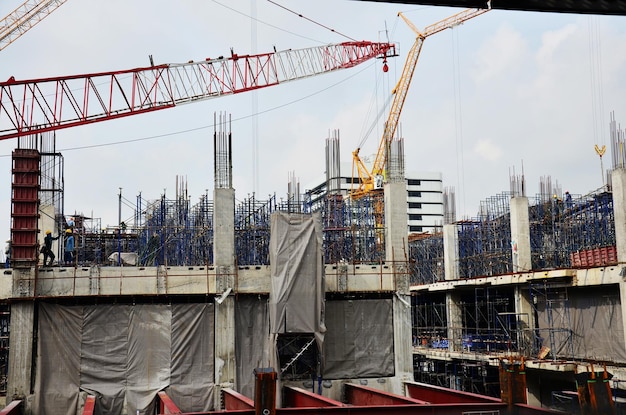 Photo des ouvriers asiatiques et des ouvriers thaïlandais utilisent des machines et des machines lourdes pour construire une nouvelle tour de construction sur un chantier de construction sur un échafaudage dans la capitale de bangkok en thaïlande
