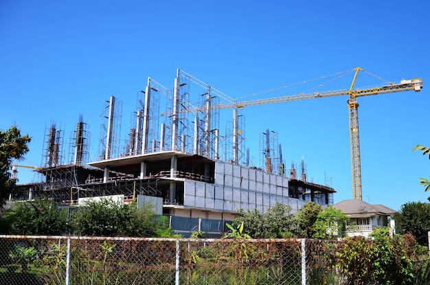 Des ouvriers asiatiques et des ouvriers thaïlandais utilisent des machines et des machines lourdes pour construire une nouvelle tour de structure sur un échafaudage sur un chantier de construction dans la capitale de Bangkok en Thaïlande