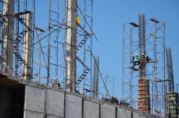 Des ouvriers asiatiques et des ouvriers thaïlandais utilisent des machines et des machines lourdes pour construire une nouvelle tour de structure sur un échafaudage sur un chantier de construction dans la capitale de Bangkok en Thaïlande