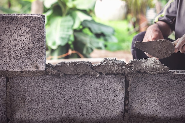 Les ouvriers du bâtiment construisent des murs de ciment avec des blocs de briques.