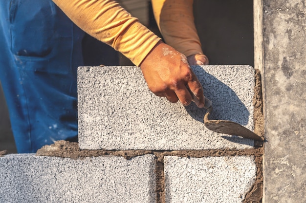 Les ouvriers du bâtiment construisent des murs de ciment avec des blocs de briques.