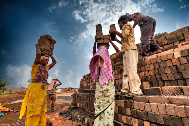 Ouvriers indiens portant des briques sur la tête jusqu'au four de l'usine.