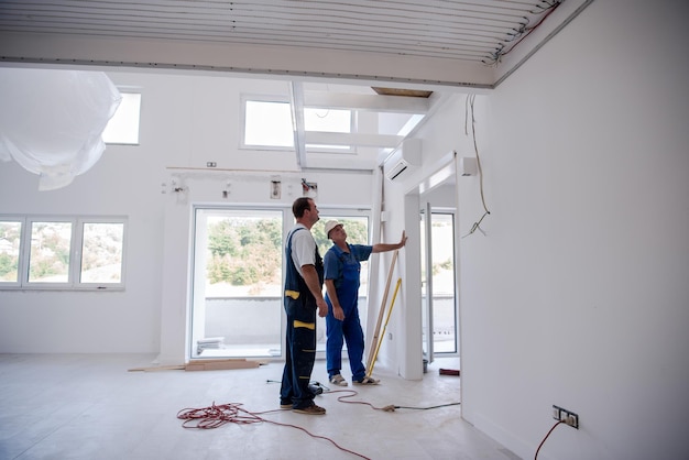 ouvriers menuisiers installant une porte intérieure en verre avec un cadre en bois dans un nouvel appartement de luxe