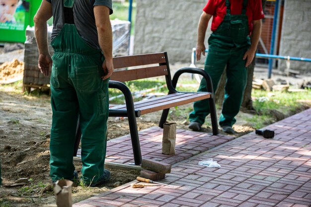 Des ouvriers mettent en place un banc de parc à un endroit désigné dans un parc de la ville.