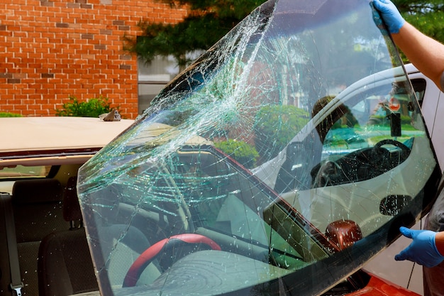 Des ouvriers spéciaux cassés de voiture de pare-brise prennent du pare-brise d&#39;une voiture en service auto