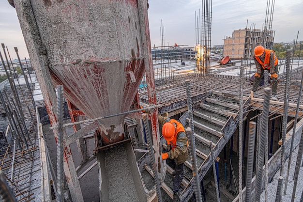 Les ouvriers sur le toit d'une infrastructure de construction avec des machines et des outils Versant du béton dans un moule