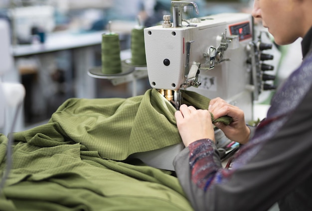 les ouvriers d'une usine de confection industrielle cousent des vêtements sur une machine à coudre