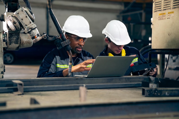 Photo ouvriers d'usine travaillant avec un bras robotique adepte dans un atelier