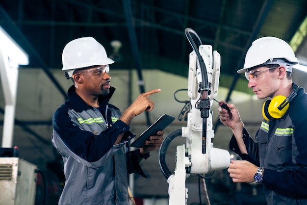 Ouvriers d'usine travaillant avec un bras robotique adepte dans un atelier