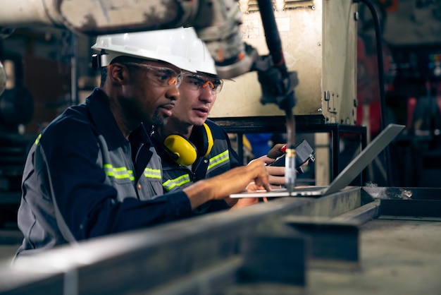 Photo ouvriers d'usine travaillant avec un bras robotique adepte dans un atelier