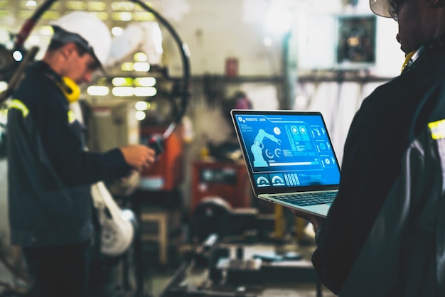 Ouvriers d'usine travaillant avec un bras robotique adepte dans un atelier