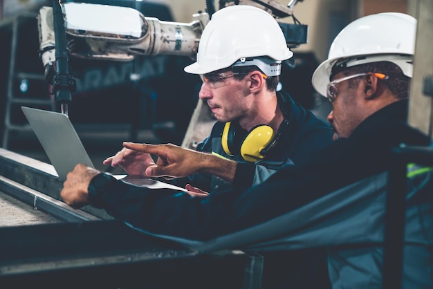 Ouvriers d'usine travaillant avec un bras robotique adepte dans un atelier