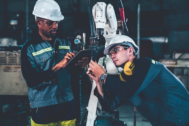 Ouvriers d'usine travaillant avec un bras robotique adepte dans un atelier