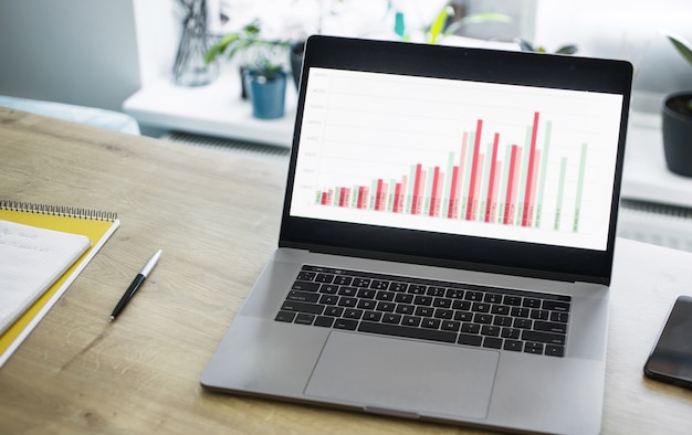 Ouvrir un ordinateur portable avec des graphiques commerciaux sur la table dans le bureau à domicile