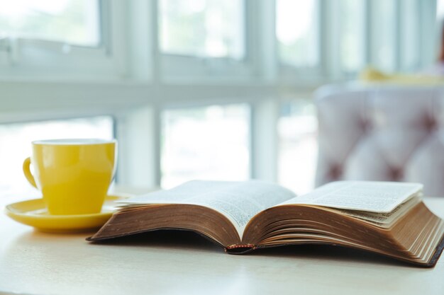 Ouvrir Le Vieux Livre Avec Une Tasse De Café Jaune Sur Le Bureau