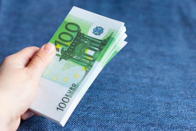 Pack d'euros en main sur fond bleu