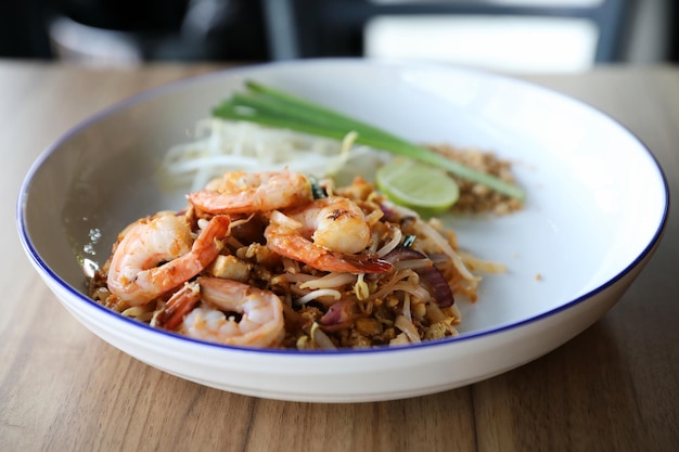 Pad thaï aux crevettes. Cuisine thaïlandaise sur fond de bois