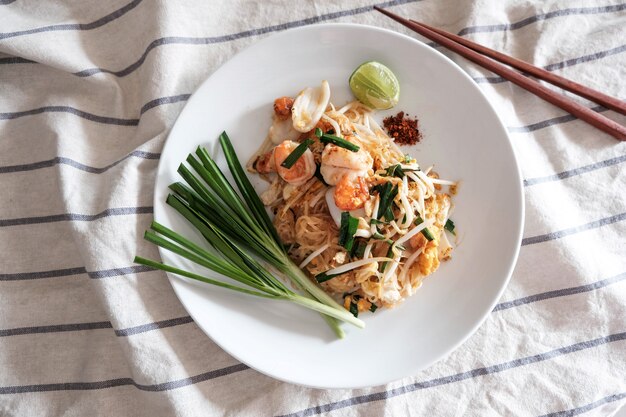 Pad Thai, crevettes roses, calmar, avec du piment, citron vert et légumes sur le côté