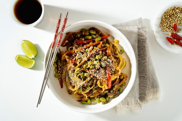 Pad thaï végétalien avec tofu et haricots edamame dans une assiette blanche