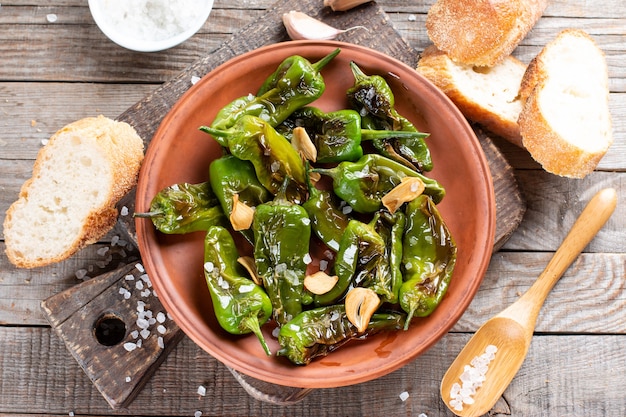 Padron de poivron vert cuit au four ou frit à l'espagnole sur une assiette sur une table en bois