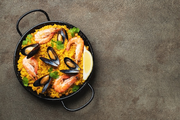 paella espagnole traditionnelle aux fruits de mer dans une casserole sur fond marron élégant, vue de dessus