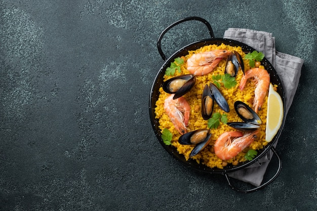 paella espagnole traditionnelle aux fruits de mer dans une casserole sur fond sombre élégant, vue de dessus