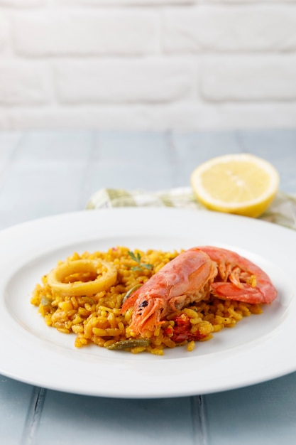 Paella espagnole traditionnelle aux fruits de mer et légumes servis sur une assiette et sur une table bleue