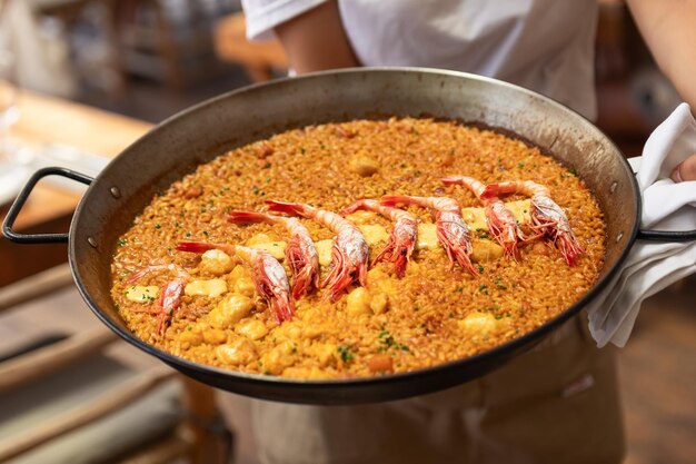 Paella de fruits de mer espagnole traditionnelle avec des crevettes dans la poêle à frire