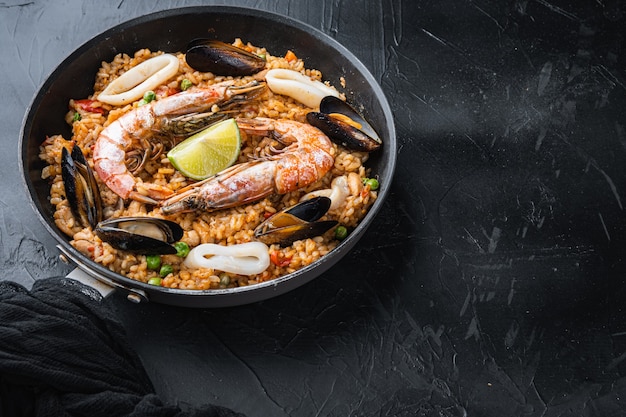 Paella Valenciana avec gambas, moules et calamars sur fond noir