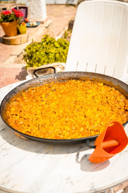 Photo paella valencienne faite sur des braises de bois et végétales lui permettant de refroidir avant de manger