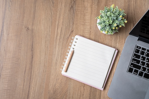 Page vierge de cahier et ordinateur portable sur une table en bois