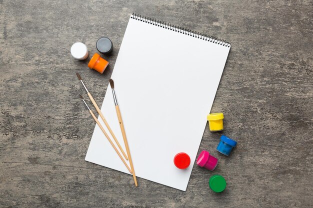 Pages d'album et peinture crayons brosse sur fond coloré Vue de dessus avec espace vide lieu de travail pour la créativité dessin de concept d'enseignement à domicile
