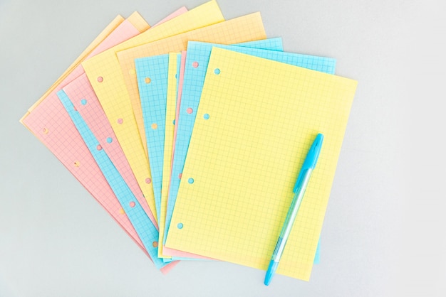 Pages à carreaux vierges multicolores d'un cahier pliant de différentes couleurs pastel éparpillées sur un bureau en argent