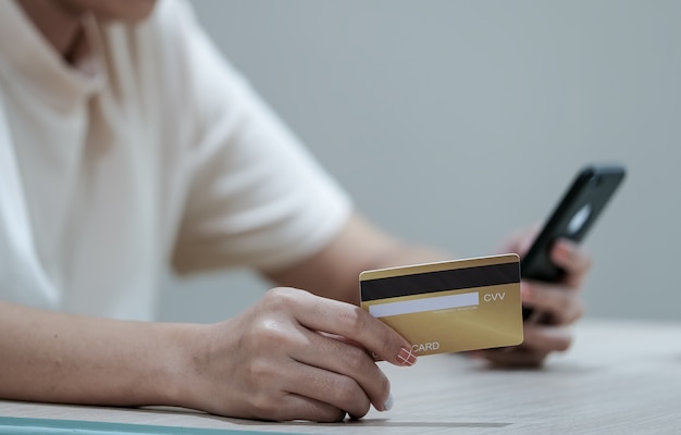 Paiement en ligne et achats, mains de femme tenant une carte de crédit et à l'aide d'un smartphone