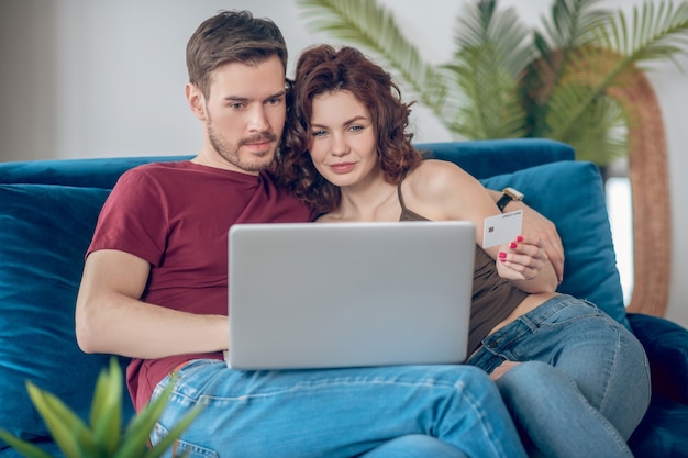 Paiements en ligne. Jeune couple mignon qui envisage d'acheter quelque chose en ligne