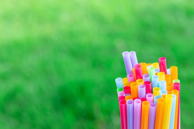 Pailles à boire de plusieurs couleurs sur un fond d'herbe verte détail flou art