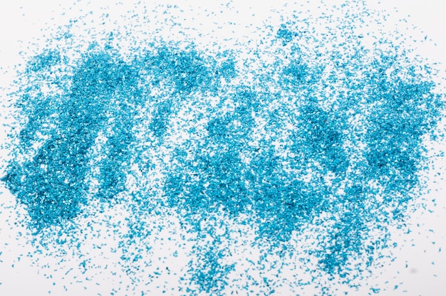 Paillettes bleues éparpillées sur fond blanc, le concept d'un fond festif.