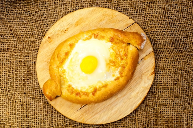 Pain Adjara khachapuri sur une planche avec du fromage et des œufs