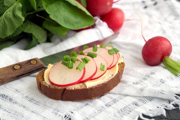 Pain au beurre et radis sur une planche de bois.