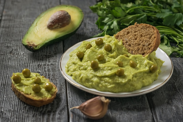 Pain au guacamole et petits pois sur une table en bois. Diète végétarienne avocat de cuisine mexicaine. Nourriture crue.