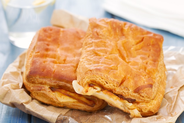 Pain au jambon et fromage avec verre d'eau sur une table en bois bleue