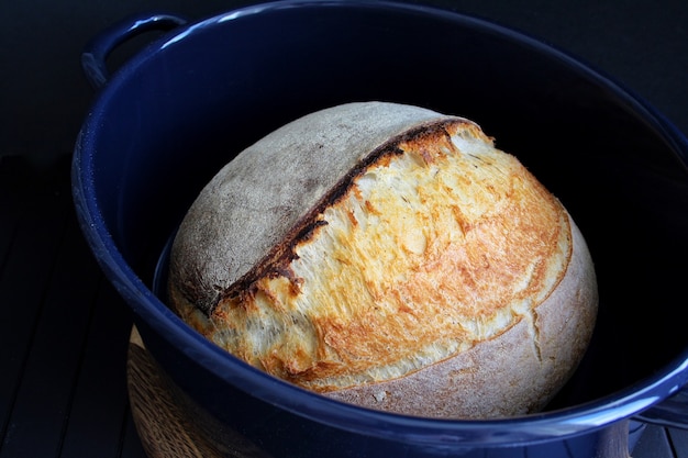 Pain au levain dans une casserole bleue sur fond noir photographie alimentaire de pain fait maison de haute qualité