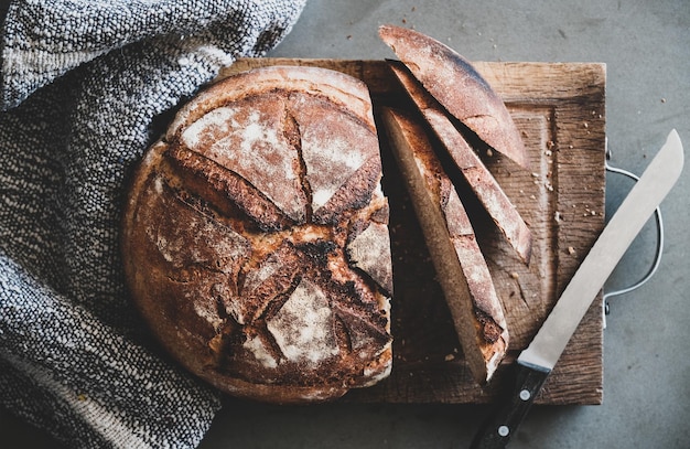 Pain au levain fraîchement cuit sur planche de bois sur fond de béton