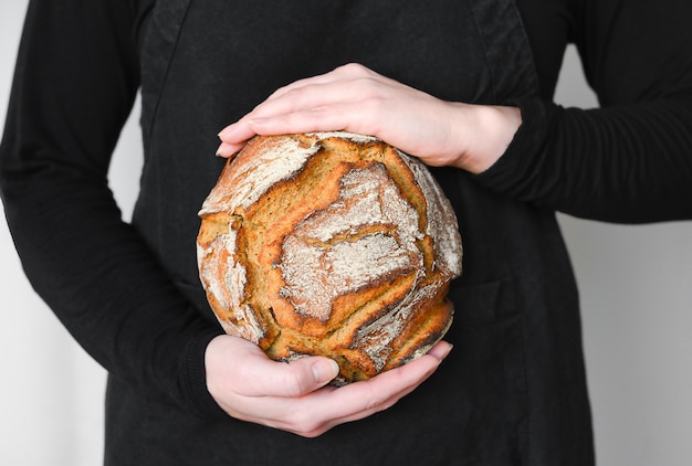 Pain au levain à grains entiers rustique, mains tenant un pain frais