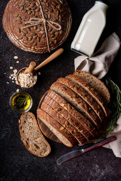 Pain au levain tranché à partir de farine de grains entiers et de graines de citrouille sur une grille d'huile d'olive et d'olive noire